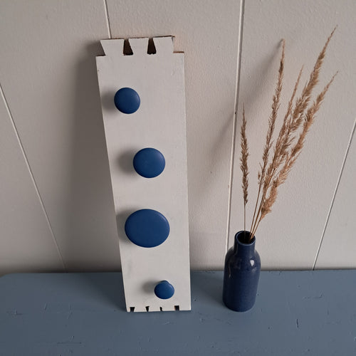 Knagerække i hvid med blå greb og en blå vase med siv