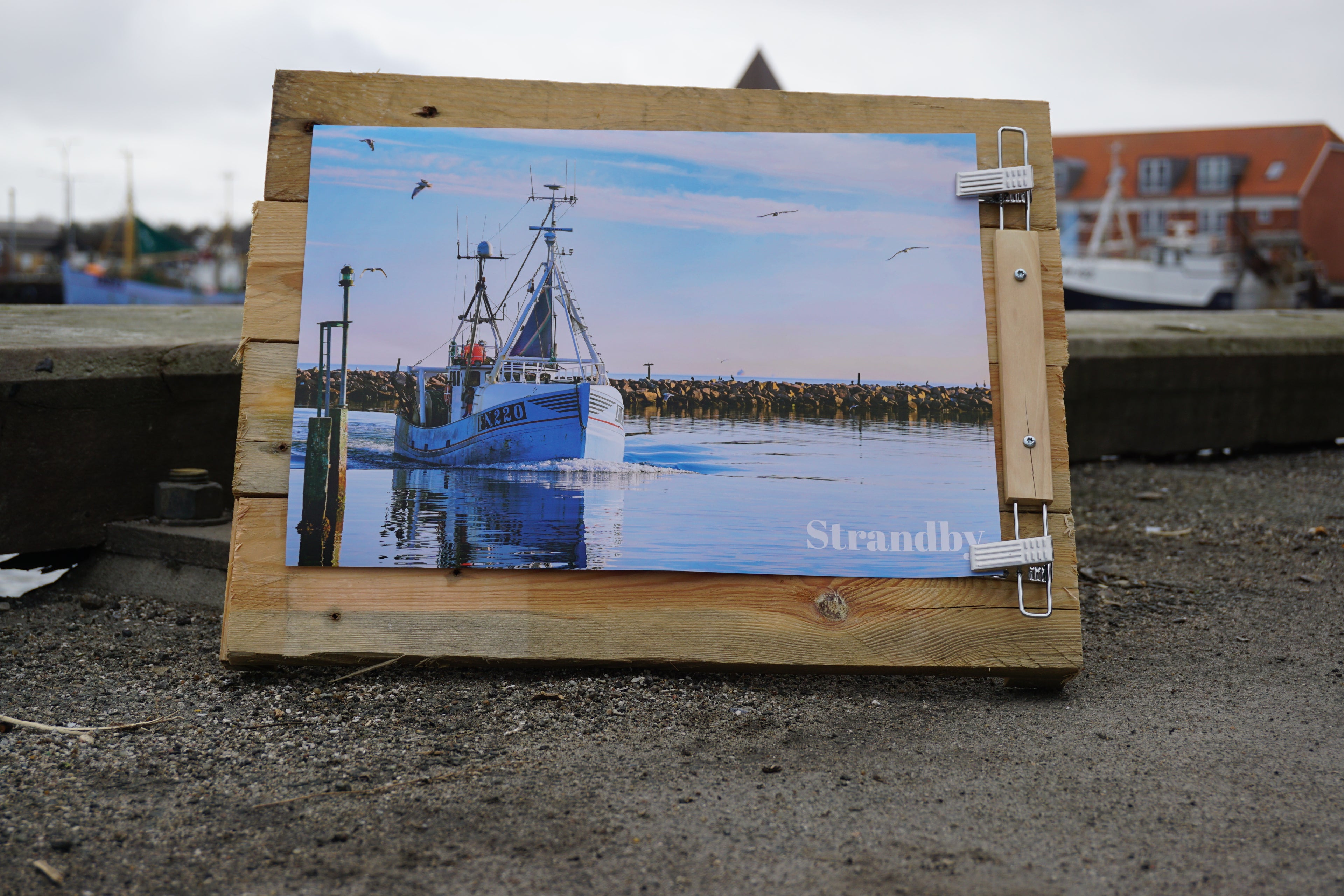 Billede af en fiskekutter ved havnen med en træramme omkring.